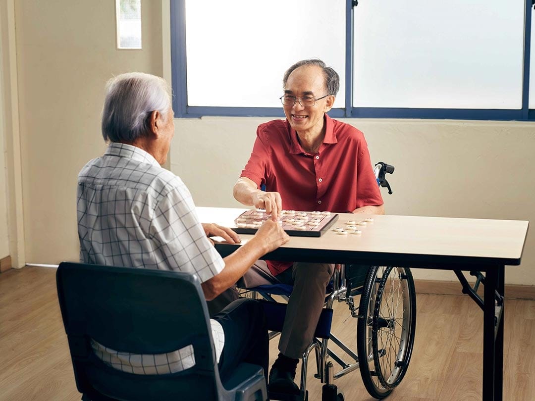 Two seniors playing a board game at a day care centre